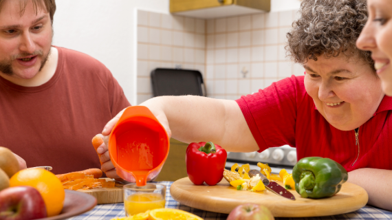 Three adults including one with learning disability, preparing food at a kitchen table