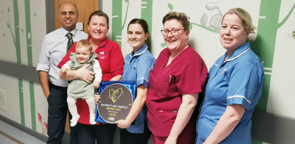 Neonatal Unit staff members with a baby and the MUM award.