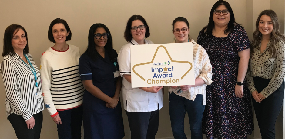 Seven staff members standing together, with two holding an Autism Impact Award logo