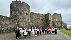 A group standing in front of Carrickfergus Castle holding a welcome banner
