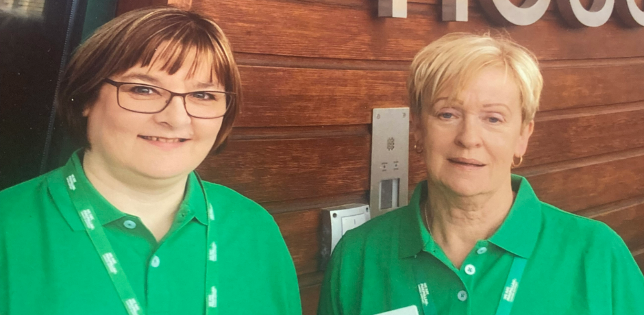 Two women wearing green t-shirts and lanyards