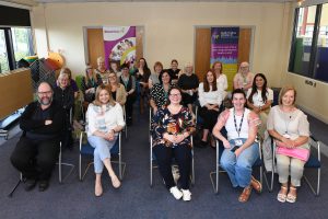 A group of people sitting on chairs in a room with pop-up banners at the back