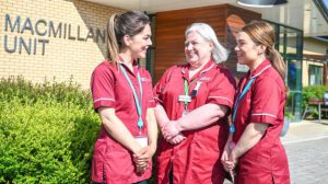 Three nurses smiling together whilst in conversation