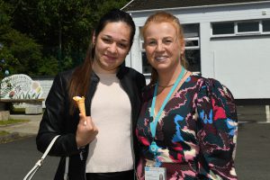 Two women stand beside each other. One is holding an ice-cream cone