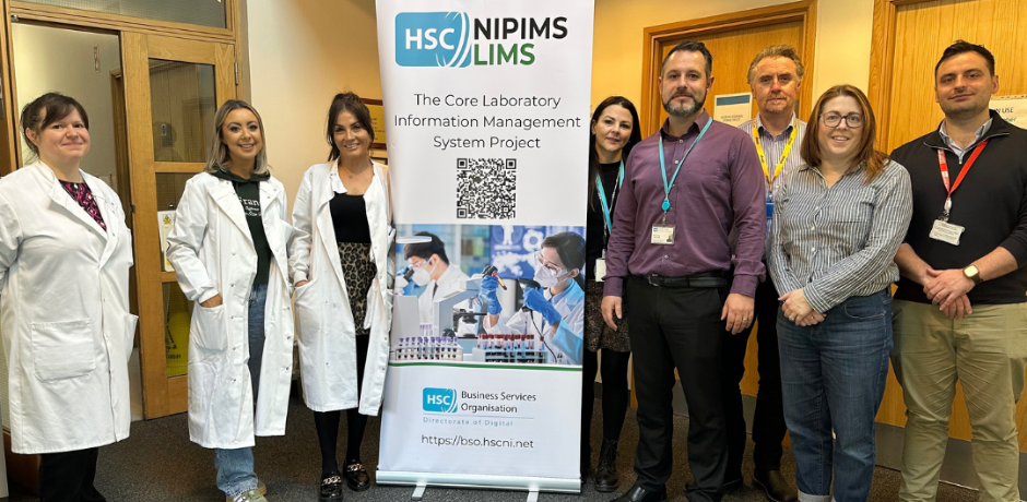 A group of staff members standing together with a pop-up banner in the middle of the group. Some of the people are wearing white coats