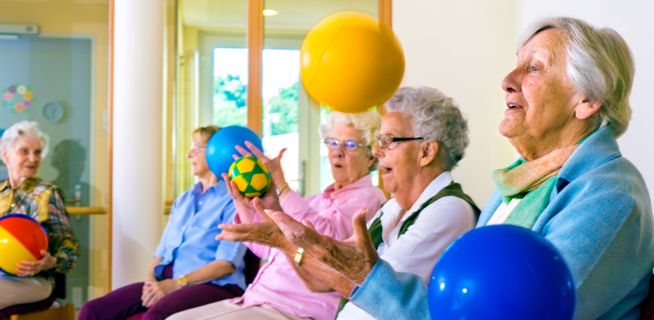 A group of older people sitting in chairs carry out exercises