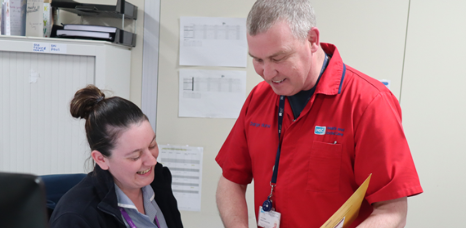 District nurse manager chatting to a nurse and showing her a file