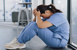 Nurse sitting on the ground with her head in her hands