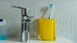 Toothbrush in a toothbrush holder, sitting beside a tap