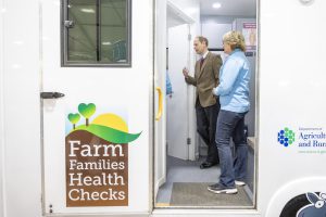 The Duke of Edinburgh stands inside the Farm Families mobile clinic. A member of staff is standing beside him.