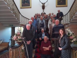 A large group of men standing together at the bottom of a large staircase inside Killymoon Castle.