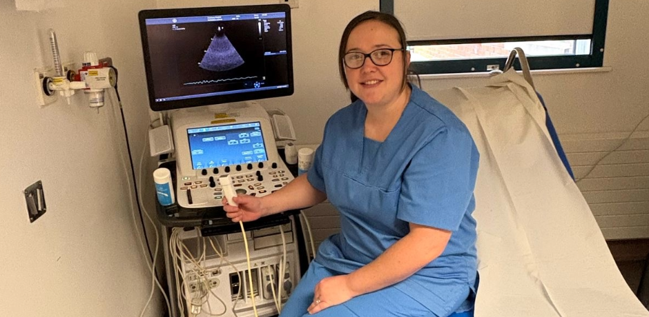 A Healthcare Scientist pictured in a clinical room beside a scanning device.