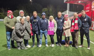A group of people stand together on a football pitch.