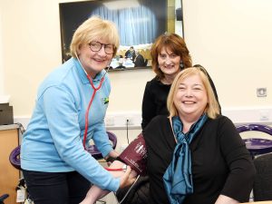 A woman sits on a chair while she gets her blood pressure checked.