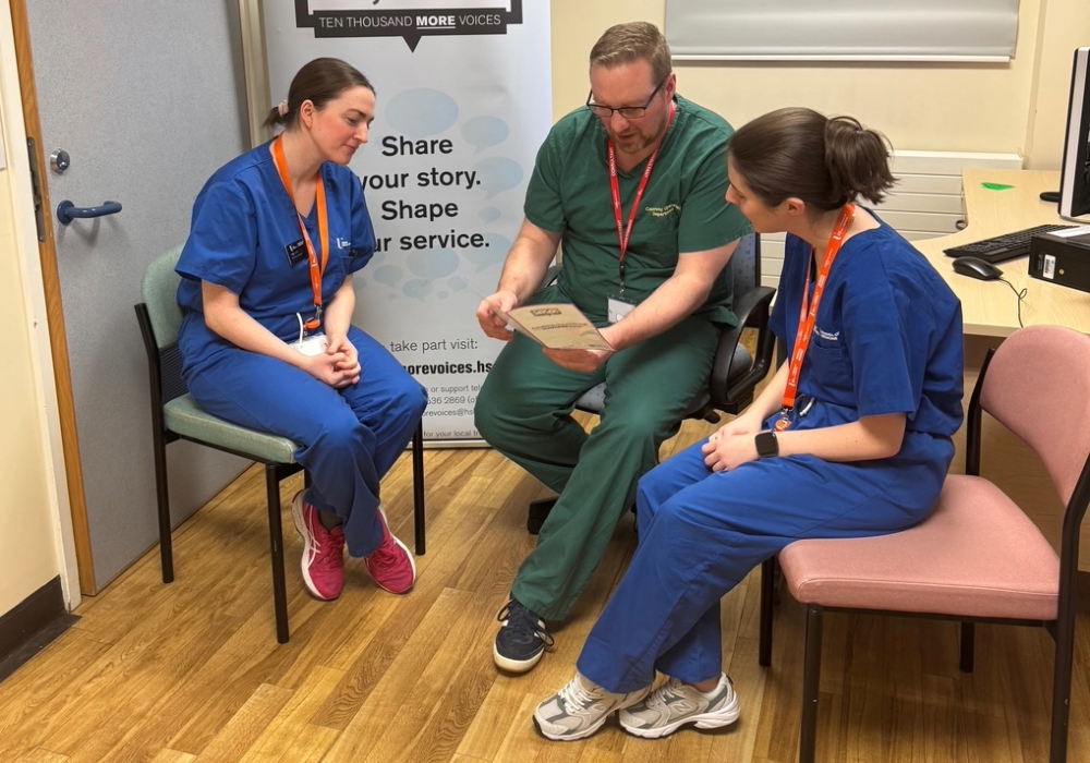 Three doctors, one male and two female, in conversation about the contents of a booklet the male doctor is holding