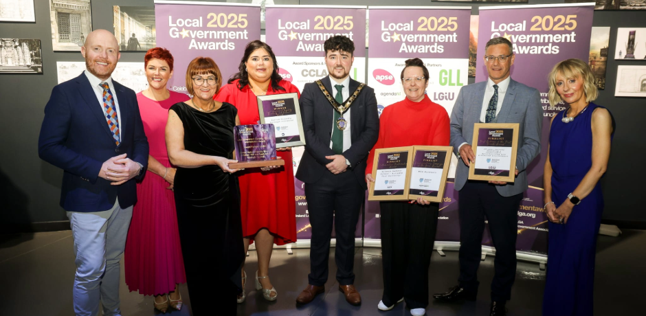 A group of people standing together. Some are holding framed certificates.