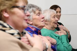  Four women sitting down taking part in a singing exercise together.
