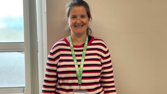A woman with a green lanyard poses for the camera.