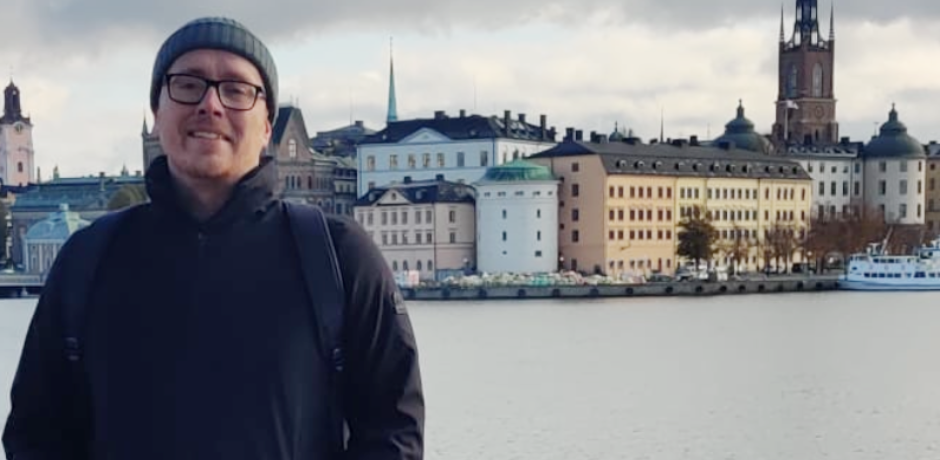 Dean Polly, with a river and buildings behind him.
