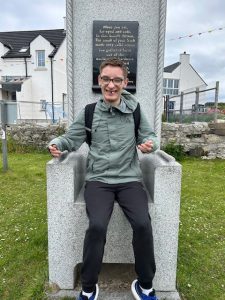 A service user from Mountfern sits on a stone chair on Rathlin Island.