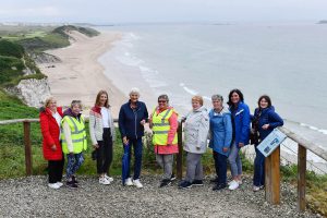 A group of women standing together in a coastal location.