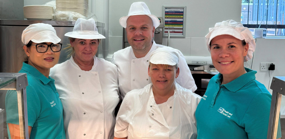 Four catering staff members standing together in their workplace.