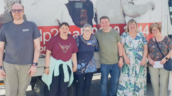 Five people standing in front of an Action Cancer branded van.