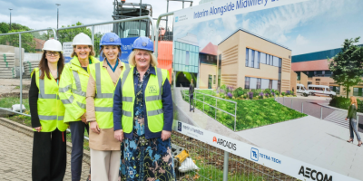 Four women hearing high viz vests and hard hats standing outside
