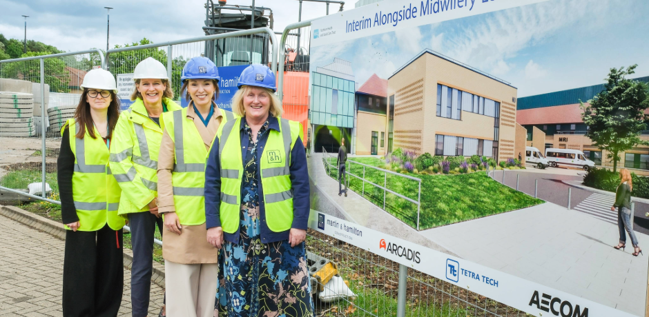 Four women hearing high viz vests and hard hats standing outside