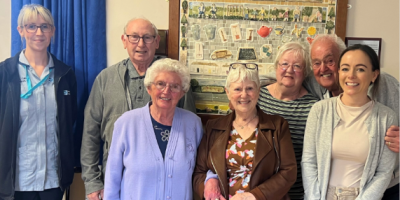 Two staff members standing with five older people