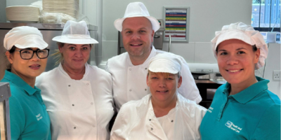 Four catering staff members standing together in their workplace.