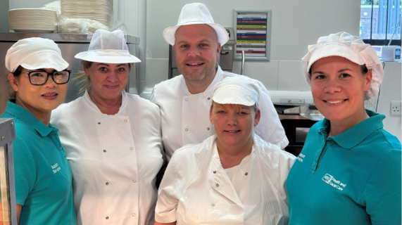 Four catering staff members standing together in their workplace.