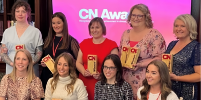 A group of people, some are sitting and some are standing behind. Each person is holding a trophy branded with CN Nutrition.