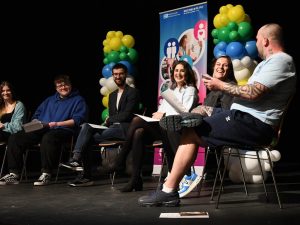 Panel of people sitting in a row holding a discussion.