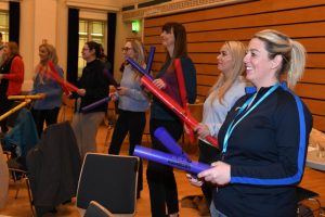 People standing holding red and blue poles used as drumsticks