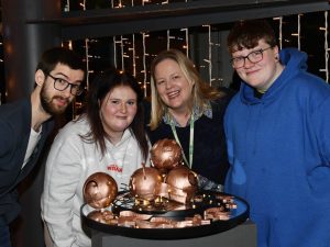 4 people, Alex Cowan (VOYPIC), Grace Wylie, Lorna Noble (Barnardo’s) and Rowan McMahon standing, standing with a centerpiece.