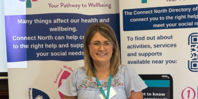 A Connect North member of staff stands in front of pop-up banners.