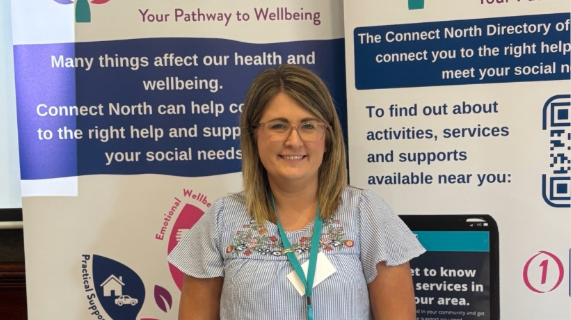 A Connect North member of staff stands in front of pop-up banners.
