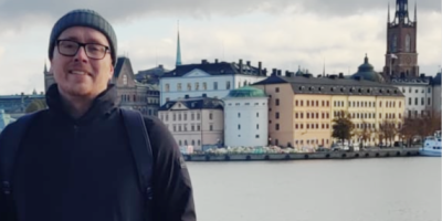 Dean Polly, with a river and buildings behind him.