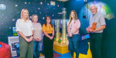 Five people standing in the new sensory room at Ellis Court.