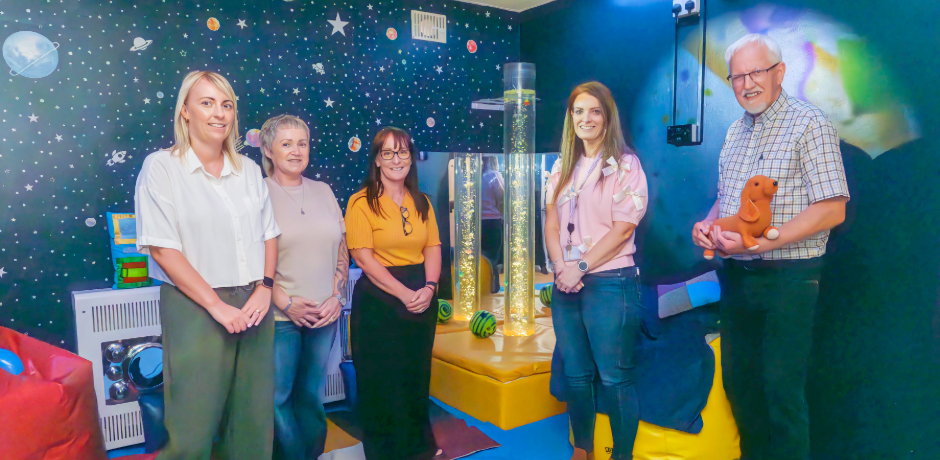 Five people standing in the new sensory room at Ellis Court.