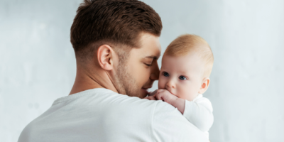 A man holds a baby on his shoulder.