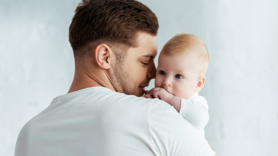 A man holds a baby on his shoulder.