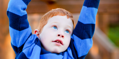 Ginger haired boy playing in a park.