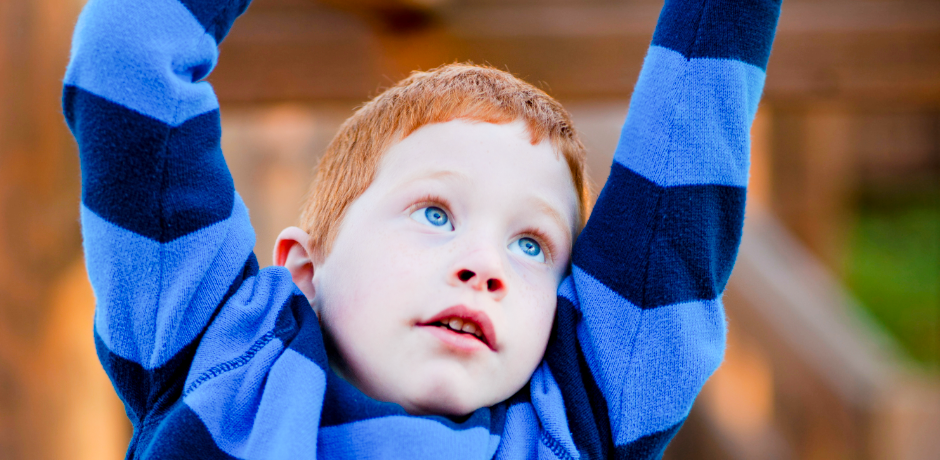 Ginger haired boy playing in a park.