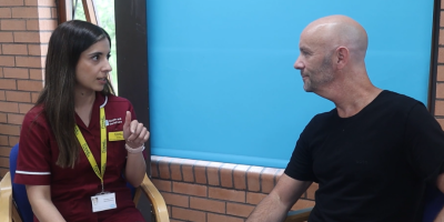 A nurse and patient sitting beside each other while having a conversation.