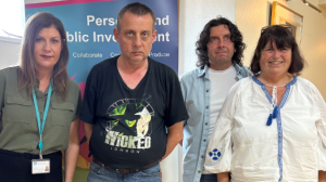 Two women and two men standing together with a pop-up banner behind them.
