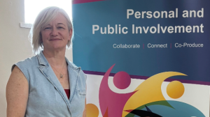 A woman stands in front of a pop-up banner about personal and public involvement.