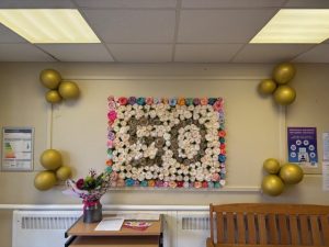 Picture of wall of roses with number 50 in centre surrounded by balloons.