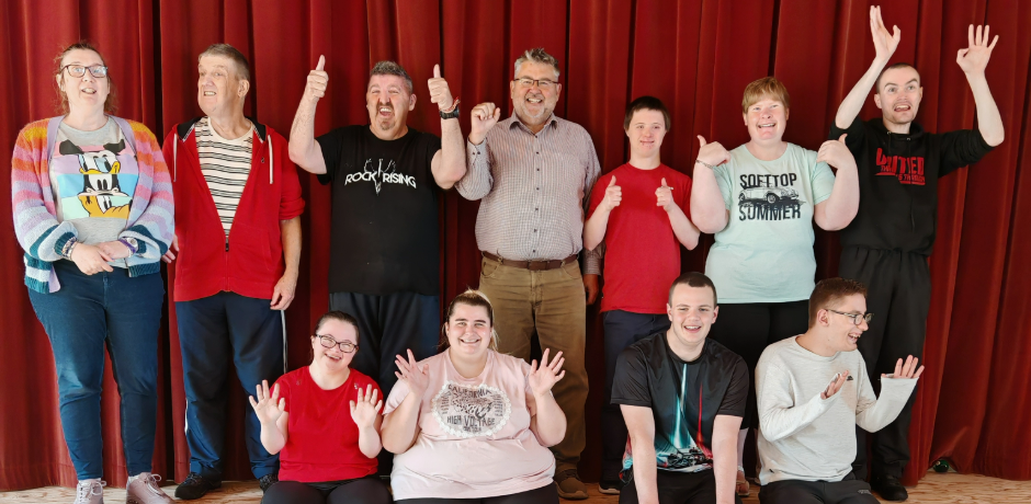 "Garth Anderson stands on stage with Day Opportunities service users.